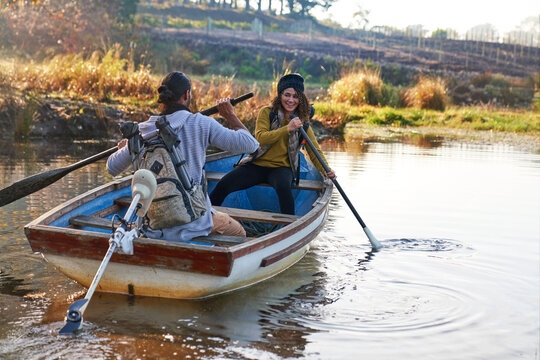 Happy young couple with oars in rowboat on sunny autumn lake
