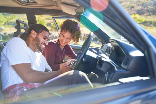 Happy Young Couple Enjoying Road Trip In Sunny Car