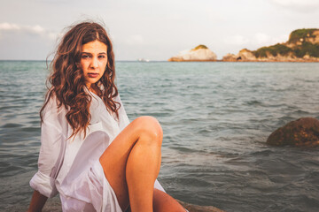Fototapeta na wymiar Sensual girl in a rocky cove with a big white shirt and a bikini.