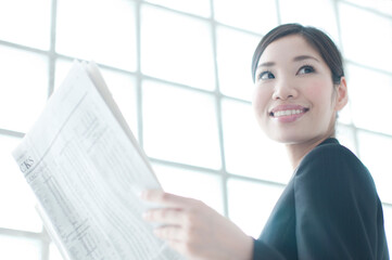 新聞を読んで微笑むOL