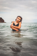 Fototapeta na wymiar Girl with a black dress in the sea at the basque coast.