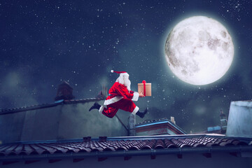 Santa Claus runs fast on a roof with a present