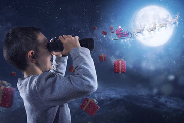 Happy child with binocular watches santa claus who fly with reindeers