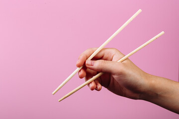 Female hand takes chopsticks sushi rolls with Chinese chopsticks. Lying on a black wooden board....