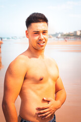 Obraz premium Young caucasian man posing at a beach in a summer morning in the basque coast.