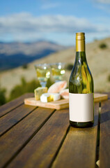 Blank label on white wine bottle with cheeseboard and view