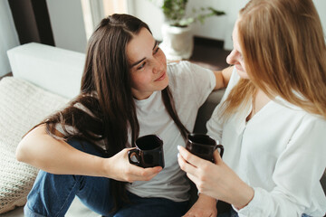 Young women drinking tea and talking indoors