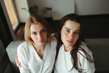 Two young women cuddling in living room