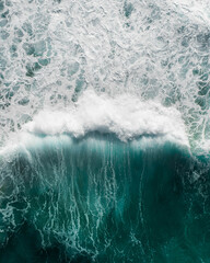 Beautiful aerial view of a wave crashing in a blue ocean during a storm