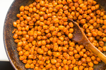Cooking chickpeas with spices in a pan, close-up