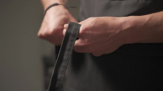 Slow motion shot: Men's hands tie a belt on a black jacket. 4k