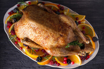 Whole roasted duck with oranges, berries and herbs. Christmas dinner meal table. Overhead, flat lay