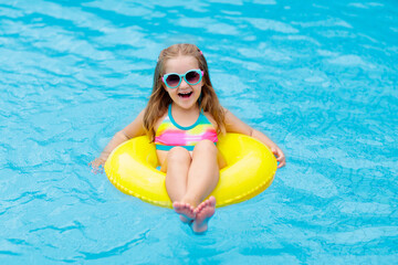 Child in swimming pool on toy ring. Kids swim.