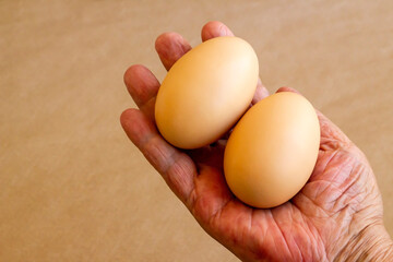 Organic,fresh large size uncooked eggs on brown background with copy space.Hand take one 
