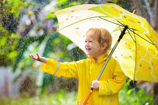 Child playing in the rain. Kid with umbrella.