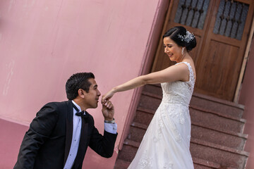 Latino Bride and Groom on door step while groom is about to kiss her hand