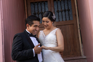 Latino Bride and Groom holding each other while groom looks at the brides ring