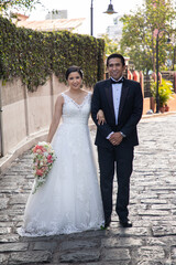 Latino Bride and Groom standing on stone road