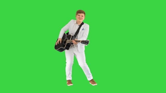 Boy in white playing acoustic guitar and dancing on a Green Screen, Chroma Key.