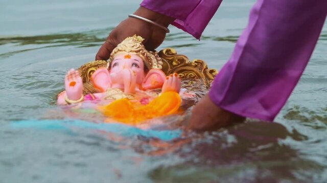 holding ganpati ganesh idol in flowing river close up slow motion