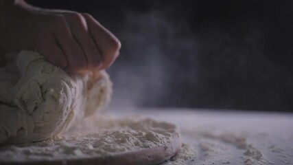 Close up view of baker kneading dough in flour on table. Hands of female chef kneading floured dough for bread.