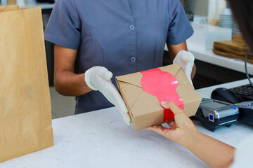 Dueño de tienda que trabaja solo con pedidos durante el brote del covid19 - Trabajadora joven con guantes quirúrgica dando comida para llevar a los clientes - Concepto de bebida de alimentos 