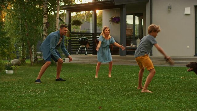 Beautiful Family of Three Play Fetch Toy Ball with Happy Brown Labrador Retriever Dog on the Backyard Lawn. Idyllic Family Has Fun with Loyal Pedigree Dog Outdoors in Summer House