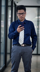 A handsome businessman wearing successful glasses is happy with a mobile phone in blue clothes.