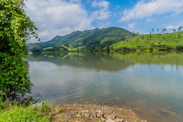 Fototapeta premium Rural landscape of lake with mountains and cloudy sky in background.