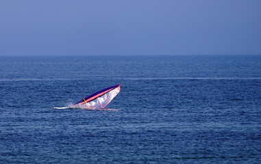 Wind surfer crashing  sail in the water in  the middle of the sea in  Gaspesie