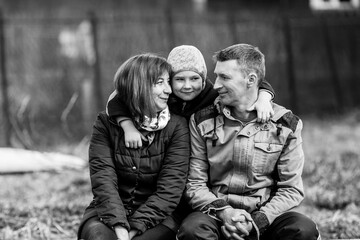 Young married couple with a young son sitting outdoors. Black and white photography.