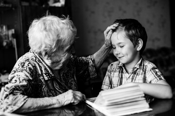 An old woman sits with his young grandson with book. Black and white photography.