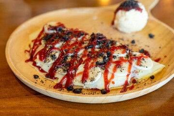 crepe with banana, whipped cream and strawberry sauce
