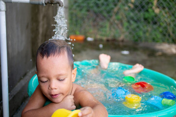a little boy bathes in a basin among concrete walls.