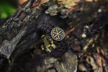 Braided bracelet made of paracord brown on the bark of a tree Kolovrat shield