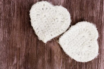 Two white knitted hearts on vintage wooden background. Beautiful handmade heart, soft heart toy. Horizontal format. Top view. Romantic background. Love concept.