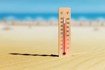 Sea coast at hot summer day. Wooden thermometer in the sand. Ambient temperature plus 39 degrees celsius