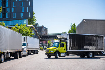 Medium-sized rig semi truck with refrigerated box trailer turns on the city street towards the...