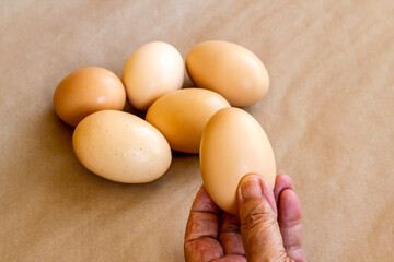 Organic,fresh large size uncooked eggs on brown background with copy space.Hand take one 