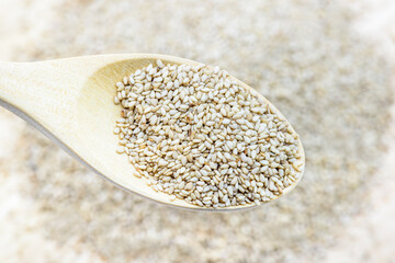 Hulled white sesame seeds in a wooden spoon. Sesame seeds have many great health benefits e.g good source of fiber, may lower cholesterol and triglycerides, nutritious source of plant protein, etc