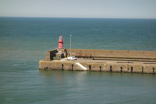 Einsamer roter kleiner Leuchtturm auf einem langen steinernen Steg in der K&uuml;ste am Meer. Dungarvan Harbour.