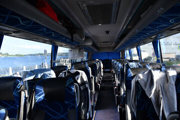 The cabin of the tour bus without people. People left their belongings on shelves and seats. Blue...