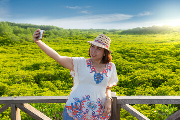 Asian women take a photo of yellow green leaves all around. Mangrove forest ecotourism Thung Prong Thong, Rayong Province, Thailand