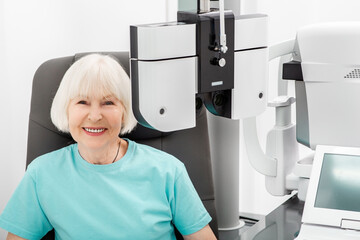 Checking smiling elderly woman's eyesight on the modern phoropter. If a woman has poor eyesight,...