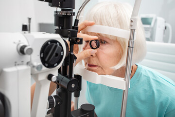 Senior woman eyesight test with binocular slit-lamp. Checking retina of a female eye close-up. Ophthalmology clinic - obrazy, fototapety, plakaty
