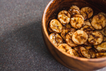 simple food ingredients, sliced banana in wooden bowl with melted cocoa powder coating