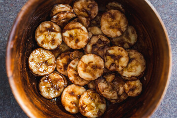 simple food ingredients, sliced banana in wooden bowl with melted cocoa powder coating