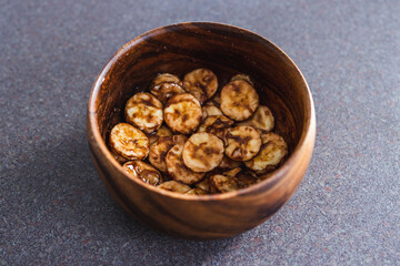 simple food ingredients, sliced banana in wooden bowl with melted cocoa powder coating