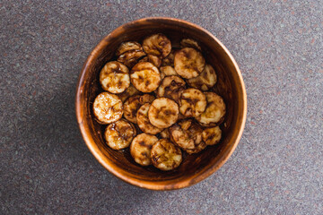 simple food ingredients, sliced banana in wooden bowl with melted cocoa powder coating