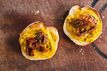simple food ingredients, bread slices with sweet potoato and kale dip topped with sundried tomatoes